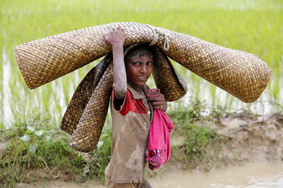 A Rohingya refugee boy reacts to the camera as he walks in the water after crossing the Bangladesh-Myanmar border in Teknaf, Bangladesh. Photo by Mohammad Ponir Hossainin