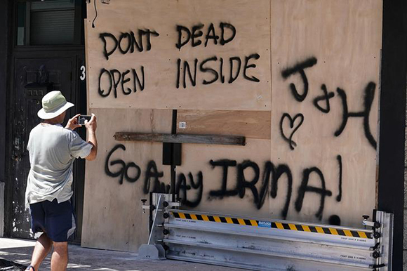 A man takes a photo of a boarded up business in advance of Hurricane Irma's expected arrival in Fort Lauderdale, Florida, U.S., September 8, 2017. 