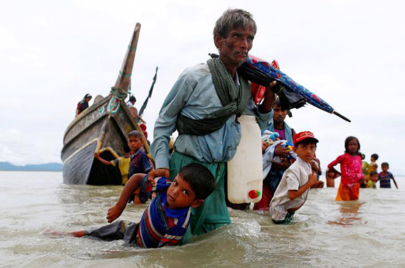 A Rohingya refugee man pulls a child as they walk to the shore after crossing the Bangladesh-Myanmar border by boat through the Bay of Bengal in Shah Porir Dwip, Bangladesh, September 10, 2017. REUTERS/Danish Siddiqui TPX IMAGES OF THE DAY