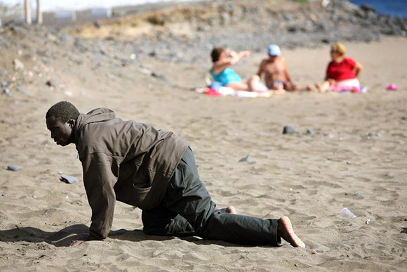  A would-be immigrant crawls on the beach after his arrival on a makeshift boat on the Gran Tarajal beach in Spain's Canary Island of Fuerteventura. Photo by Juan Medina 