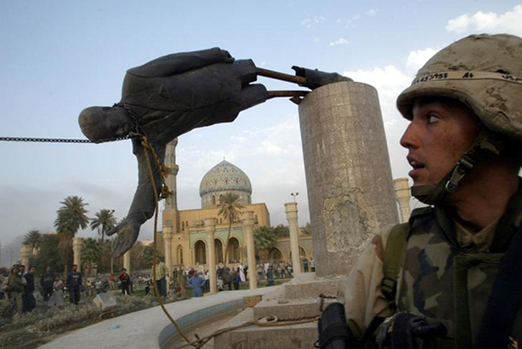  U.S. Marine Corp Assaultman Kirk Dalrymple watches as a statue of Iraq's President Saddam Hussein falls in central Baghdad . Photo by Goran Tomasevic 