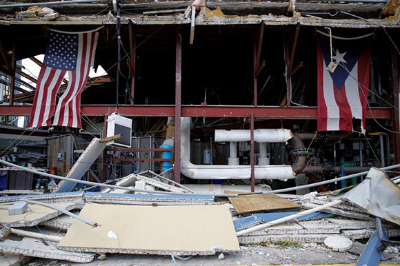  U.S. and Puerto Rico flags hang on a damaged church after the area was hit by Hurricane Maria in Carolina, Puerto Rico September 26, 2017. Photo by Carlos Garcia Rawlins 