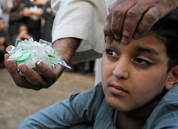  Twelve-year-old Ahmed El Helal's father holds a handful of shattered glass near his face in a small village in Assiut, Egypt, September 18, 2017. Picture taken September 18, 2017. Photo by Mohamed Abd El Ghany 