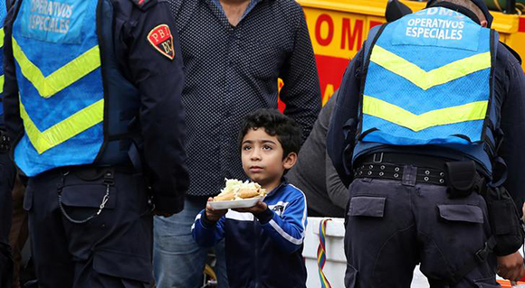 Jesus Roldan, 6, offers a plate of food to a police officer next to a collapsed building at Alvaro Obregon Avenue in the Condesa neighborhood, after an earthquake in Mexico City, Mexico September 29, 2017. Photo by Nacho Doce
