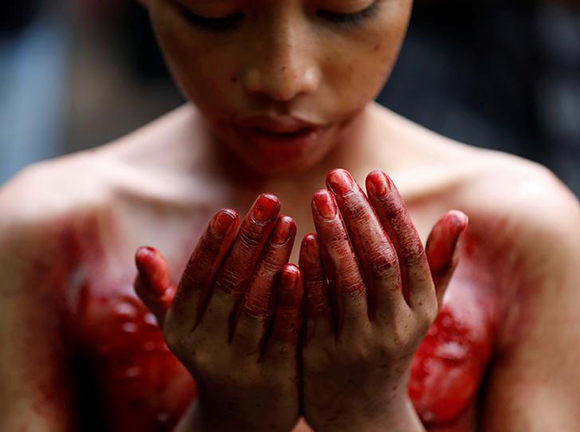A Shi'ite Muslim boy prays after he beat himself at a mosque during a religious festival marking Ashura, in central Yangon, Myanmar October 1, 2017. Photo by Soe Zeya Tun