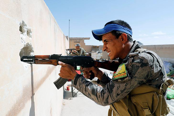 Members of Syrian Democratic Forces take up positions on the rooftop of a house during a battle with Islamic State militants in Raqqa, Syria October 1, 2017. Photo by Erik De Castro