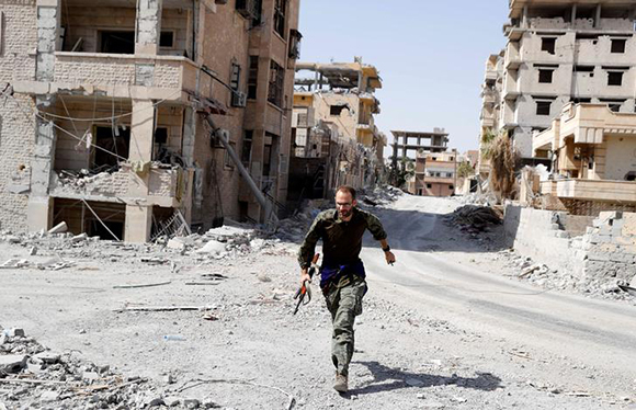 A British volunteer fighter of Syrian Democratic Forces runs for cover to avoid sniper fire of Islamic State militants, at the frontline in Raqqa, Syria October 7, 2017. Photo by Erik De Castro 