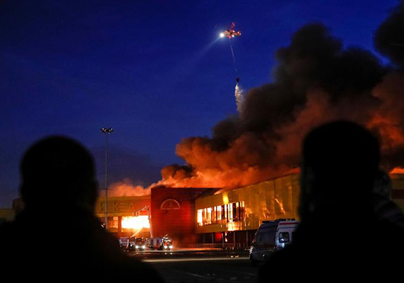 People watch as a helicopter dumps water on a fire at a construction goods market on the northwestern edge of Moscow, Russia October 8, 2017. Photo by Maxim Shemetov 