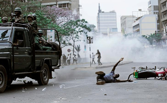 A supporter of Kenyan opposition National Super Alliance (NASA) coalition, lies on the ground after he was hit by a police truck during a protest along a street in Nairobi, Kenya, October 11, 2017. Photo by Thomas Mukoya 