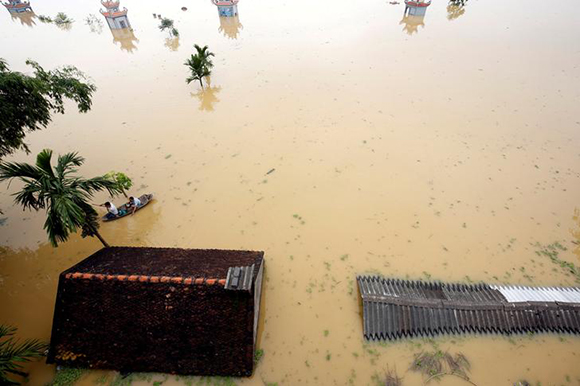  Farmers paddle in a boat at a flooded village after a tropical depression in Hanoi, Vietnam. Photo by Kham 