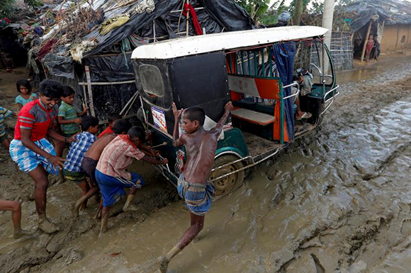  Rohingya refugee children push a tuk-tuk stuck in the mud at Kutupalong refugee camp near Cox's Bazar, Bangladesh October 13, 2017. Photo by Jorge Silva 