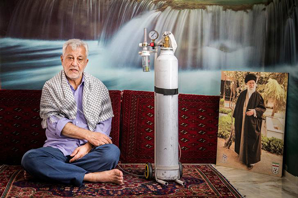  Naser Mohmmadi, an Iranian patient, poses for a photo next to a picture of Iran’s Supreme Leader Ayatollah Ali Khamenei in his home in Tehran, Iran. Photo by Nazanin Tabatabaee Yazdi 