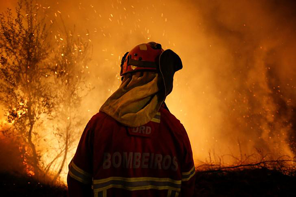  A firefighter is seen near flames from a forest fire in Cabanoes, near Lousa, Portugal, October 16, 2017. Photo by Pedro Nunes 