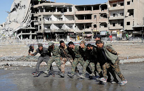  Fighters of the Syrian Democratic Forces (SDF) dance along a street in Raqqa, Syria October 18, 2017. Photo by Erik De Castro 