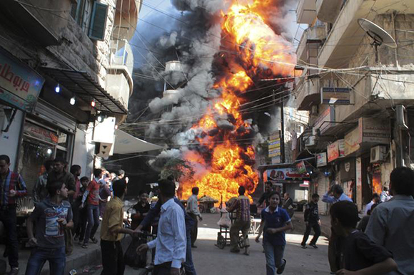 Residents run from a fire at a gasoline and oil shop in Aleppo's Bustan Al-Qasr neighbourhood. Photo by Haleem Al-Halabi 