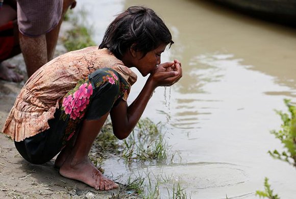  A Rohingya refugee girl drinks river water as she waits for boat to cross the border through Naf river in Maungdaw, Myanmar. Photo by Mohammad Ponir Hossain 