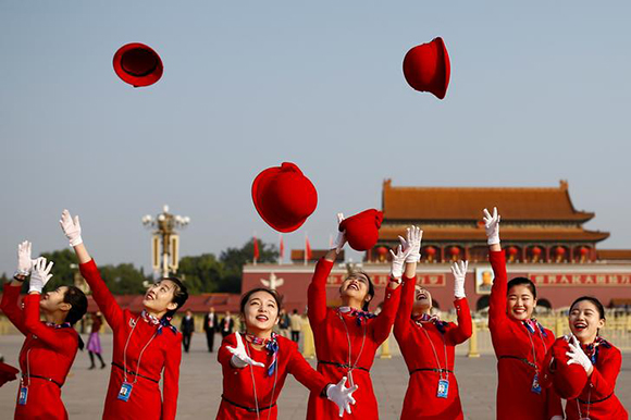  Ushers throw their hats in the air as they pose for photographers at the Tiananmen Square before the start of the closing session of the 19th National Congress of the Communist Party of China, in Beijing, China October 24, 2017. Photo by Thomas Peter 