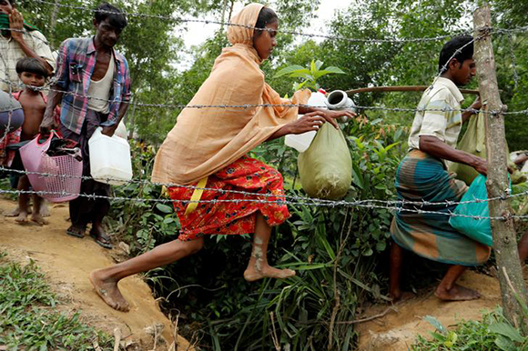  A Rohingya refugee woman, who crossed the border from Myanmar two days before, jumps during her walk to the Kotupalang refugee camp near Cox's Bazar, Bangladesh. Photo by Jorge Silva 