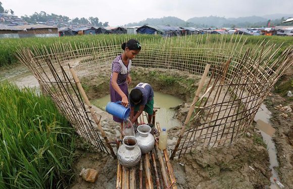  Rohingya refugee children collect water from a shallow well, dug from the sand outside their shelter at Uchiprang refugee camp near Cox’s Bazar, Bangladesh. Photo by Adnan Abidi 