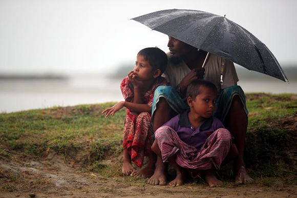  Rohingya refugees shelter from the rain as they wait to receive permission from the Bangladeshi army to continue their way after crossing the Bangladesh-Myanmar border, at a port in Teknaf, Bangladesh, October 31, 2017. Photo by Hannah McKay 