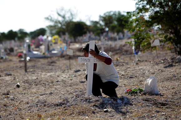  A woman puts a cross on a common grave at San Rafael cemetery during day of the Dead on the outskirts of Ciudad Juarez, Mexico. Photo by Jose Luis Gonzalez 