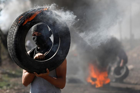  A Palestinian protester carries a burning tire during clashes with Israeli troops, in the West Bank village of Kofr Qadom, near the West Bank city of Nablus November 3, 2017. Photo by Mohamad Torokman 