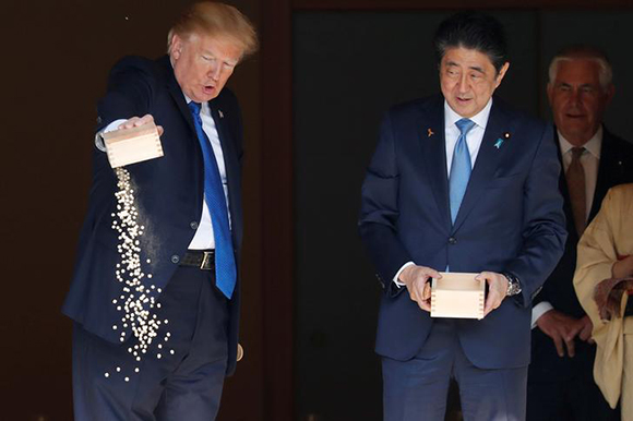  U.S. President Donald Trump pours fish food out as Japan's Prime Minister Shinzo Abe looks on while they were feeding carp before their working lunch at Akasaka Palace in Tokyo, Japan November 6, 2017. Photo by Jonathan Ernst 