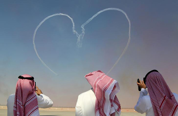 Visitors take pictures as Al Fursan aerobatic team of the United Arab Emirates Air Force performs during the Dubai Airshow in Dubai, UAE November 13, 2017. Photo by Satish Kumar