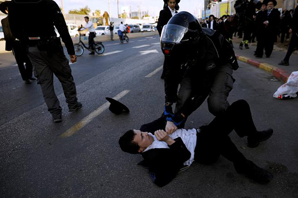  An Israeli police officer tries to move an ultra-Orthodox Jewish man away, during a demonstration against the detention of members of their community, who failed to report to a military recruiting office, in Bnei Brak, near Tel Aviv, Israel November 20, 2017. Photo by Amir Cohen 