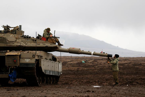  An Israeli soldier sits atop a tank and his comrade stands nearby in the Israeli-occupied Golan Heights, close to Israel's frontier with Syria November 22, 2017. Photo by Ammar Awad 