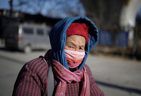  A woman walks on a street at a village, which is mainly inhabited by migrant workers, in Tongzhou district of Beijing, China December 16, 2017. Photo by Jason Lee 
