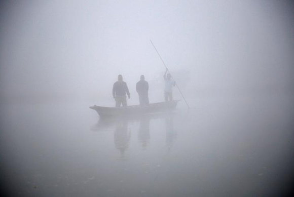  People ride on a boat to reach the bank of Rapti River during the foggy winter morning at Sauraha in Chitwan, Nepal December 26, 2017. Photo by Navesh Chitrakar 