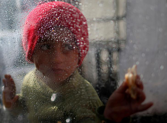  A Palestinian girl looks through a plastic sheet as raindrops are seen, outside her family's house in Al-Shati refugee camp in Gaza City January 17, 2018. Photo by Mohammed Salem 