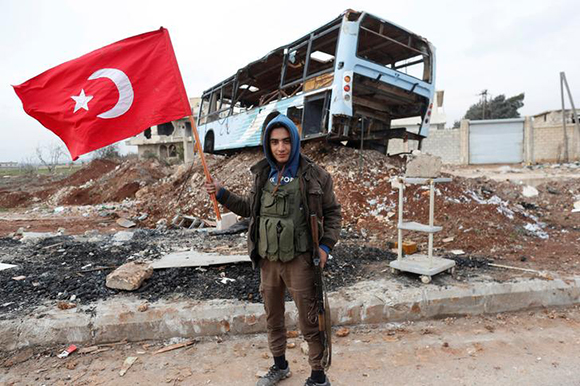  A Turkey-backed Free Syrian Army fighter holds a makeshift Turkish flag as he patrols on a road near Azaz, Syria January 21, 2018. Photo by Osman Orsal 