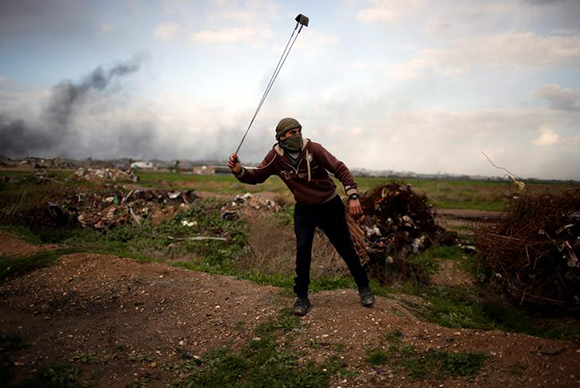  A Palestinian protester holds a sling as he poses for a photograph at the scene of clashes with Israeli troops near the border with Israel, east of Gaza City, January 19, 2018. Photo by Mohammed Salem 