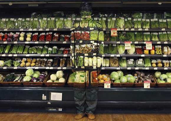  Artist Liu Bolin demonstrates an art installation by blending in with vegetables displayed on the shelves at a supermarket in Beijing November 10, 2011. Photo by China Daily 