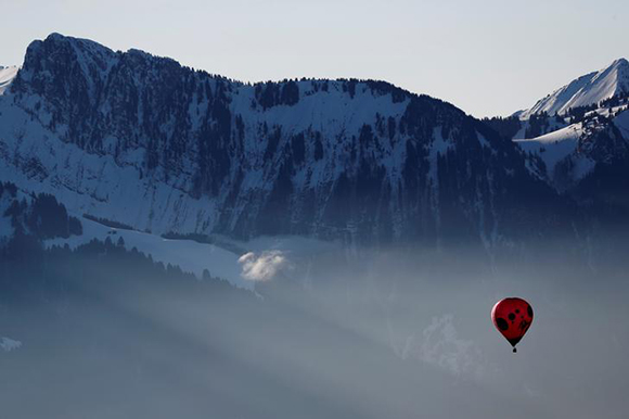  A balloon flies over Swiss mountains during the International Hot Air Balloon Week in Chateau-d'Oex, Switzerland January 27, 2018. Photo by Stefan Wermuth 