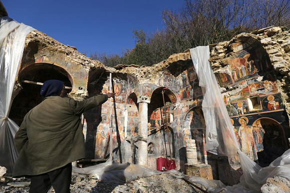  A man points out a damaged fresco in The Orthodox Church of Saint Athanasios in Leshnica, Saranda, Albania January 25, 2018. Photo by Florion Goga 