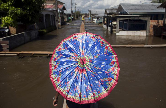  A resident walks on a makeshift walkway above a flooded street from the rising Rio Solimoes, one of the two main branches of the Amazon River, in Careiro da Varzea of Amazonas State, Brazil. Photo by Bruno Kelly 