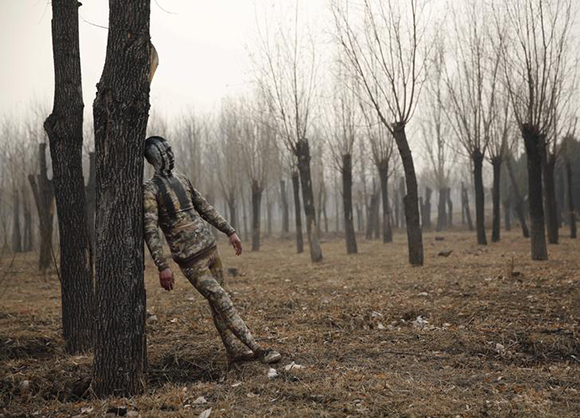  A model painted in camouflage colours to blend in with the background practises posing for Chinese artist Liu Bolin's artwork "Dongji", or Winter Solstice, on the second day after China's capital Beijing issued its second ever "red alert" for air pollution, in Beijing, China, December 20, 2015. Photo by Kim Kyung-Hoon 