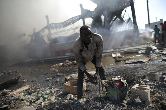  A man looks for goods amid the rubble outside of the Marche Hyppolite (Hyppolite Market), also known as Marche en Fer (Iron Market), after a fire that affected part of the market and the surrounding stands in Port-au-Prince, Haiti, February 13, 2018. Photo by Andres Martinez Casares 