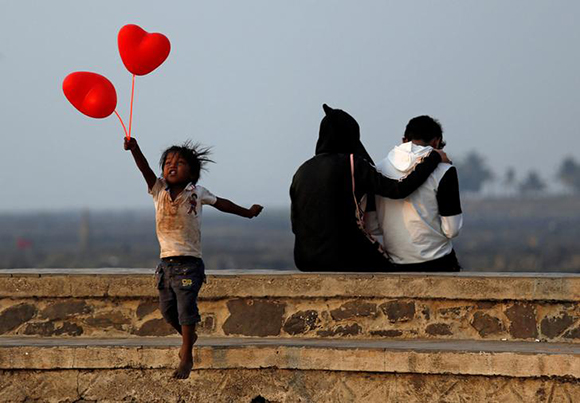  A child jumps from a promenade after attempting to sell heart-shaped balloons to a couple on Valentine's Day in Mumbai, India February 14, 2018. Photo by Francis Mascarenhas 