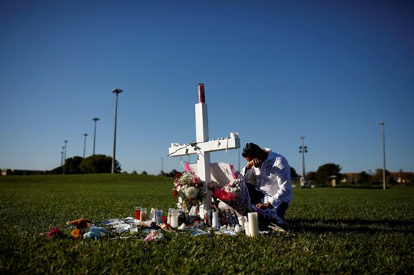  Joe Zevuloni mourns in front of a cross placed in a park to commemorate the victims of the shooting at Marjory Stoneman Douglas High School, in Parkland, Florida, U.S., February 16, 2018. Photo by Carlos Garcia Rawlins 