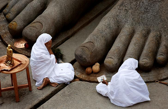  Devotees sit at the feet of the monolithic statue of Jain god Gomateshwara as they celebrate the Mahamastakabhisheka, or head anointing ceremony of the statue, in Shravanabelagola, India February 17, 2018. Photo by Abhishek N. Chinnappa 