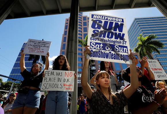  A protester holds a defaced placard at a rally calling for more gun control three days after the shooting at Marjory Stoneman Douglas High School, in Fort Lauderdale, Florida, U.S.,February 17, 2018. Photo by Jonathan Drake 