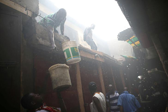  Men help firefighters to extinguish a fire at a market in Port-au-Prince, Haiti February 18, 2018. Photo by Andres Martinez Casares 