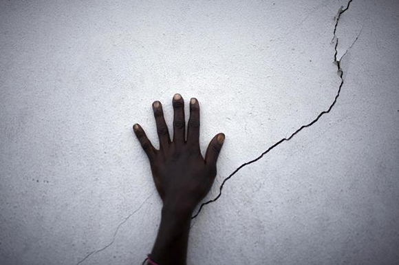  A woman puts her hand near a crack on a wall as she waits for food distribution in Port-au-Prince, Haiti. Photo by Carlos Barria 