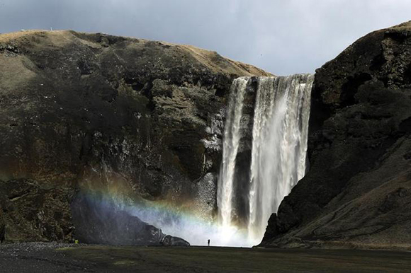  A woman stands near a waterfall that has been dirtied by ash that has accumulated from the ash plume of an erupting volcano near Eyjafjallajokull, Iceland. Photo by Lucas Jackson 