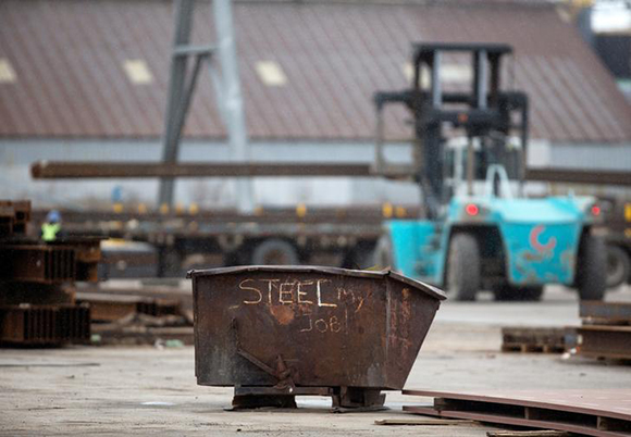  A garbage bin with the words "STEEL MY JOB!" painted on it sits in a storage yard where structural steel is loaded onto a truck in the portlands of Hamilton, Ontario, Canada, March 9, 2018. Photo by Peter Power 