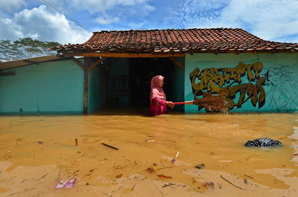  A woman villager cleans garbage in front of her house as flood hits Tanjungsari village in Tasikmalaya, Indonesia, February 23, 2018. Photo by Adeng Bustomi 